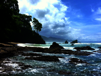 Tropische Küste mit Felsen, tiefblauem Wasser, Sandstrand und Palmen
