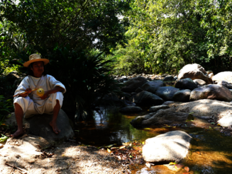 Junger Kogi sitzt an Fluss in der Sierra Nevada de Santa Marta