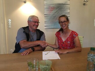 Katja Wiese, Geschäftsführerin von Naturefund, und ein Eigentümer eines Grundstückes sitzen an einem Tisch und schütteln sich die Hand